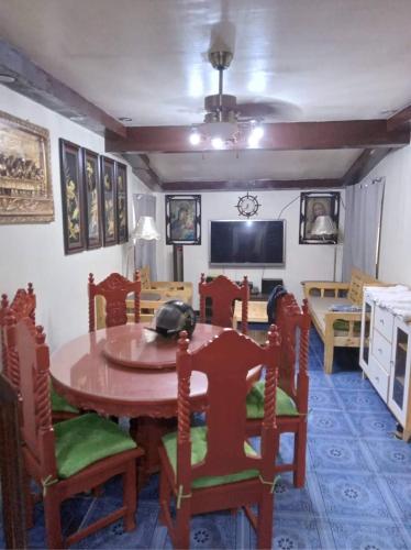 Balili Property at Metro Manila Hills Subd Rodriguez Rizal في مانيلا: غرفة طعام مع طاولة وكراسي وتلفزيون