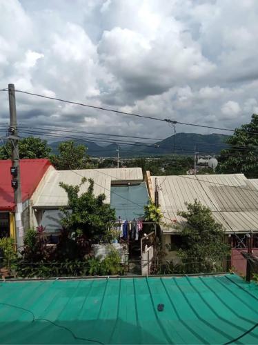 Balili Property at Metro Manila Hills Subd Rodriguez Rizal في مانيلا: إطلالة على منزل ذو سقف أخضر