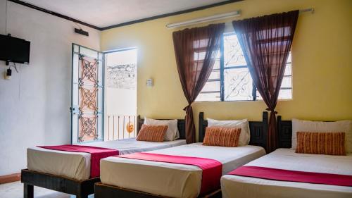 two beds in a room with two windows at Hotel Mucuy in Mérida