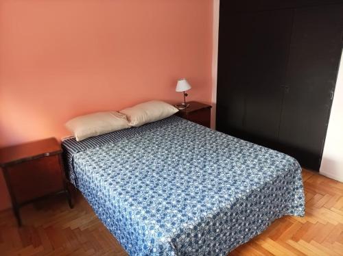a bedroom with a bed with a blue comforter at Caballito deluxe Apart in Buenos Aires