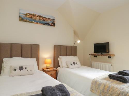 a bedroom with two beds and a tv on the wall at Foulsyke Farm Cottage in Saltburn-by-the-Sea
