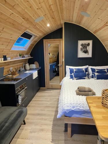 a bedroom with a large bed and a wooden ceiling at Craigend Farm Holiday Pods - The Curly Coo in Dumfries