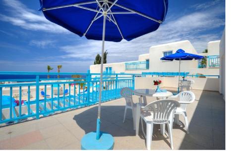 a table and chairs with an umbrella on a balcony at Sunny Hill Hotel Apartments in Paphos City