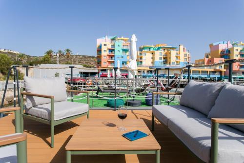 une terrasse avec des canapés et une table avec un verre de vin dans l'établissement The Homeboat Company Albufeira, à Albufeira