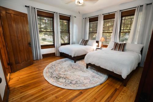 2 łóżka w pokoju z oknami i dywanem w obiekcie Gulf Coast Craftsman - Cozy, Charming & Central! w mieście Gulfport