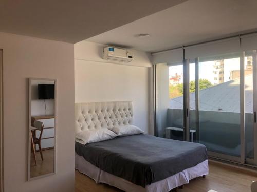 ein Schlafzimmer mit einem Bett und einem großen Fenster in der Unterkunft Espectacular Departamento en San Telmo - Piscina, Lavadero y Parrilla in Buenos Aires