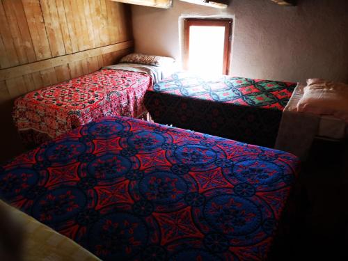 a room with three beds and a window at Pinnettu sardo casa di campagna in ecosistema insetti e animaletti simpatici in condivisione,Leggere attentamente Prima di prenotare in Oliena