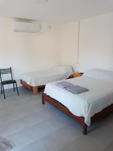 a room with two beds and a chair in it at Departamento Chacabuco 2 in San Fernando del Valle de Catamarca