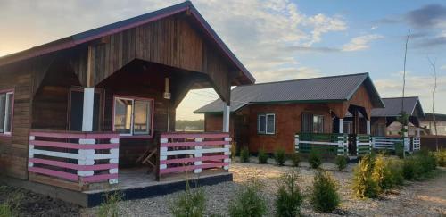 een houten huis met een hek ervoor bij Hobby Land Ranch Horse's barn guesthouse in Găneasa