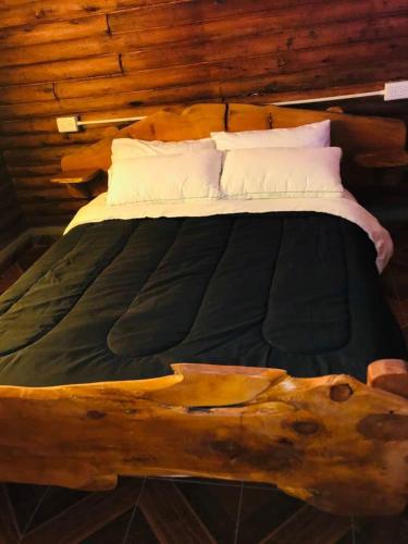 a bed made out of a log with two pillows at Cabañas Achalay in Valle Hermoso