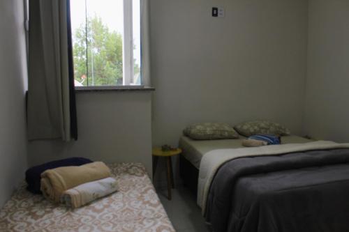 ein kleines Zimmer mit 2 Betten und einem Fenster in der Unterkunft apartamento fruto da terra 302 VISTA LATERAL MONTANHAS in Caparaó Velho
