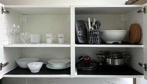 a white cabinet filled with dishes and utensils at FELLINI SUITES Lungomare near the sea in Catania