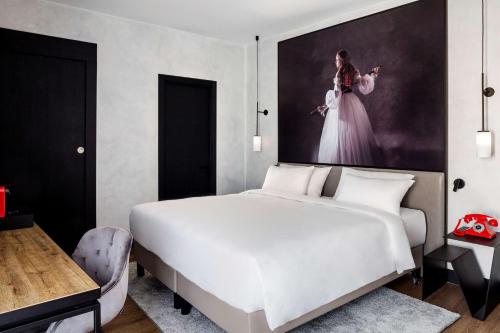 a bedroom with a white bed and a painting of a woman at Radisson RED Madrid in Madrid