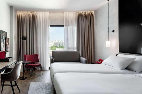 a hotel room with two beds and a desk at Radisson RED Madrid in Madrid