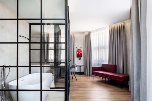 Habitación con baño con banco rojo y bañera. en Radisson RED Madrid en Madrid
