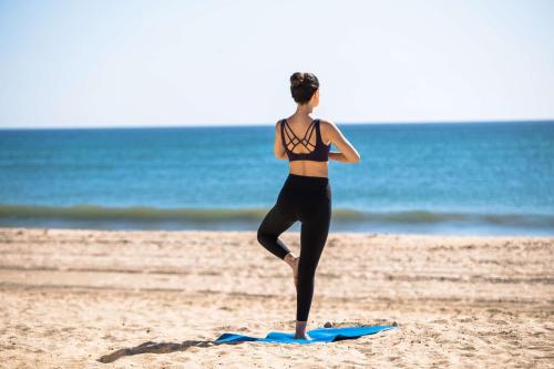 a woman standing on a surfboard on the beach at Banyan Tree Tamouda Bay in Fnidek