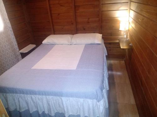 a small bedroom with a bed in a wooden cabin at Cabanas Alamanda do Rosa in Imbituba
