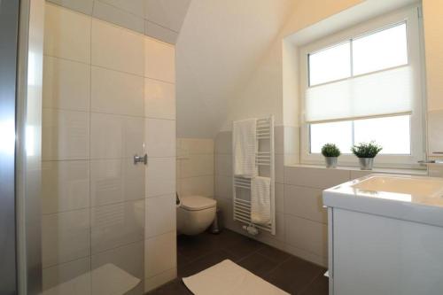 ein Bad mit einem WC, einem Waschbecken und einem Fenster in der Unterkunft Ferienhaus im Angerdorf in Cuxhaven