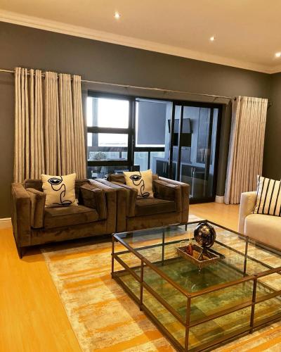 a living room with two couches and a glass table at Waves Edge CP3 in Cape Town