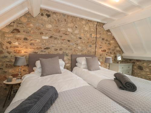 two beds in a room with a stone wall at The Linhay in Axminster