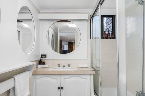 a white bathroom with a sink and a shower at Surf Haven opposite Clarkes Beach pool walk to CBD in Byron Bay