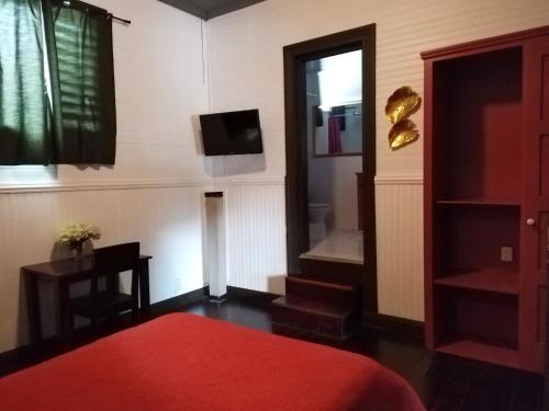 a bedroom with a red bed and a television at Casa Aldea in San José