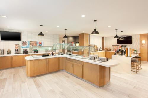 une grande cuisine avec des placards en bois et des comptoirs blancs dans l'établissement Staybridge Suites - San Bernardino - Loma Linda, à San Bernardino