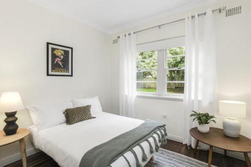 ein weißes Schlafzimmer mit einem Bett und einem Fenster in der Unterkunft Katoomba Getaway 3 Bedroom Villa in Katoomba