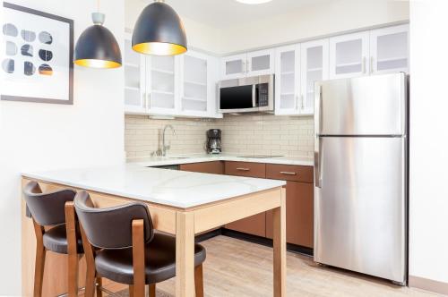 a kitchen with a stainless steel refrigerator and a table at Staybridge Suites - San Bernardino - Loma Linda in San Bernardino
