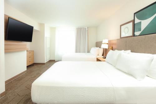 a hotel room with two beds and a flat screen tv at Staybridge Suites - San Bernardino - Loma Linda in San Bernardino