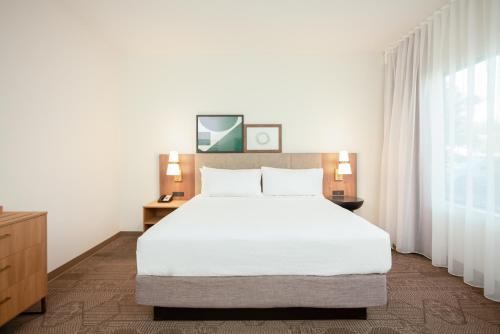 a bedroom with a white bed and a large window at Staybridge Suites - San Bernardino - Loma Linda in San Bernardino