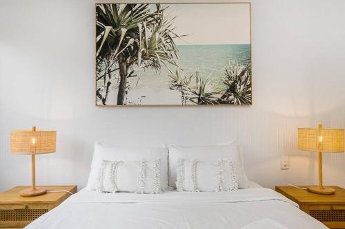a bedroom with a bed with a picture on the wall at Castaway opposite Clarkes Beach in Byron Bay