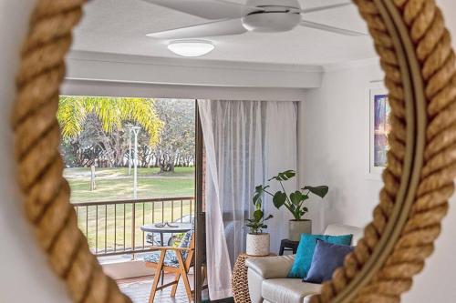 a mirror reflecting a living room with a couch and a balcony at Castaway opposite Clarkes Beach in Byron Bay