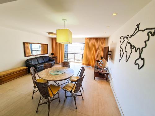 uma sala de estar com uma mesa e cadeiras e um sofá em Apartamento pé na areia - Praia do Forte em Cabo Frio