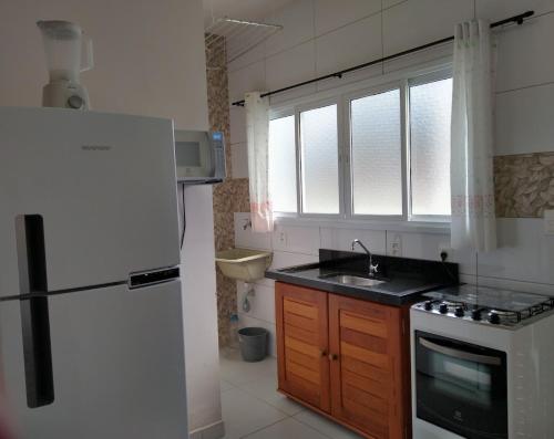 uma cozinha com um frigorífico branco e um lavatório em Canto Verde Aptos II em Caraguatatuba
