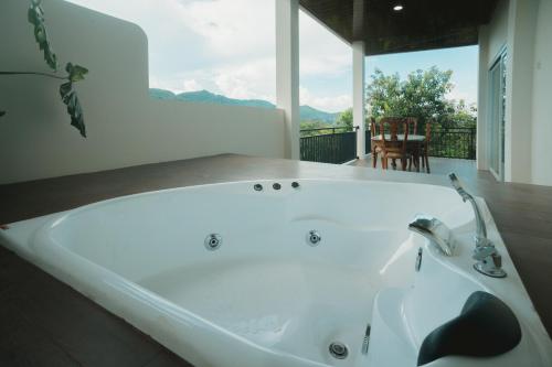 a bath tub in a room with a large window at Hakata Lejja near Natural Hot spring in Batu-Batu