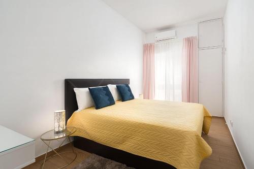 a bedroom with a bed with yellow sheets and blue pillows at My Place @ Faro Skyline in Faro