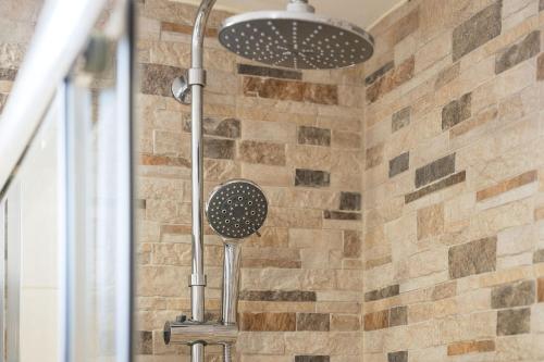 a shower head in a bathroom with a brick wall at My Place @ Faro Skyline in Faro