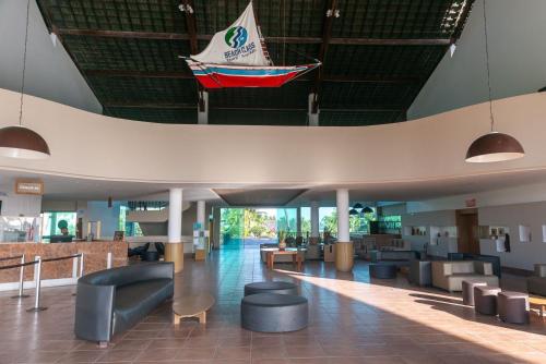 a lobby with couches and a boat hanging from the ceiling at Flat ou Bangalo Luxo Beach Class Beira Mar Muro Alto in Porto De Galinhas