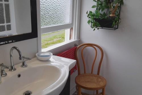 a bathroom with a sink and a chair next to a window at Turret House in Featherston