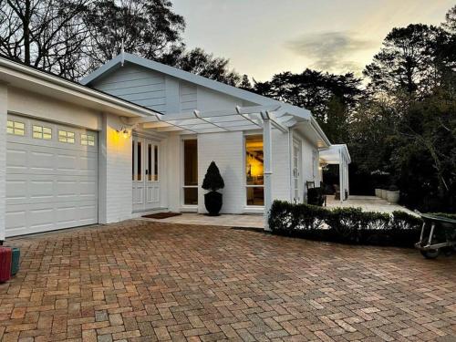 ein weißes Haus mit einer steinernen Einfahrt davor in der Unterkunft Sunnyside Luxurious 4BR Art Villa, Fireplace, Village 2mins in Wentworth Falls