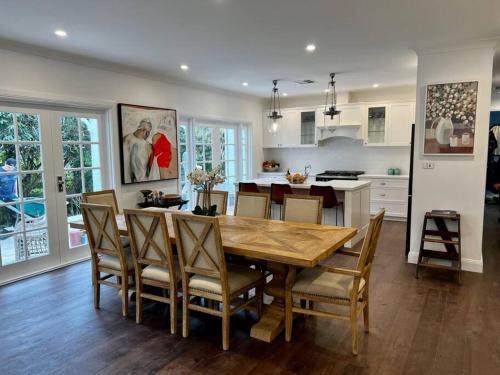uma cozinha e sala de jantar com uma mesa de madeira e cadeiras em Sunnyside Luxurious 4BR Art Villa, Fireplace, Village 2mins em Wentworth Falls