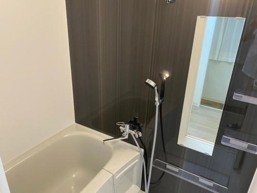 a bathroom with a bath tub and a shower at ホテルトーマス牧志 in Naha