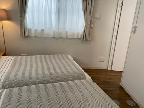 a bedroom with a bed and a window with curtains at ホテルトーマス牧志 in Naha