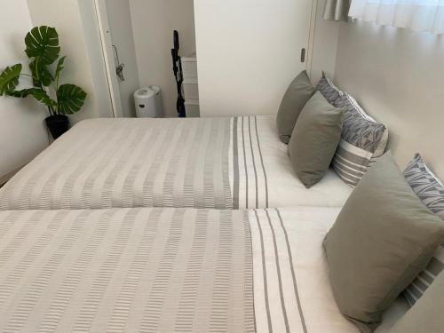 a white bed with pillows on it in a bedroom at ホテルトーマス牧志 in Naha