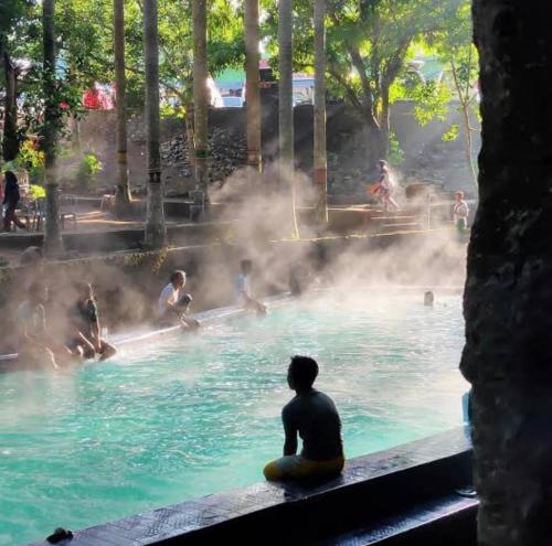 eine Person, die im Pool im Wasser sitzt in der Unterkunft Hakata Lejja near Natural Hot spring in Batu-Batu
