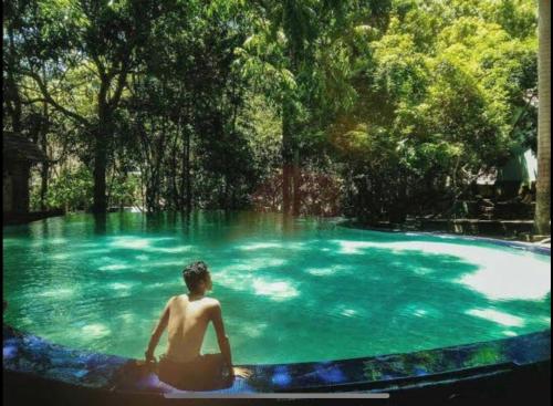 a man sitting in a pool of blue water at Hakata Lejja near Natural Hot spring in Batu-Batu