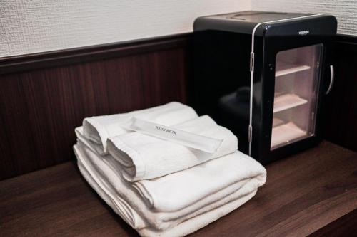 a pile of towels sitting on a shelf next to a microwave at SAMURAI STAY 洗足池-male only 男性専用 in Tokyo