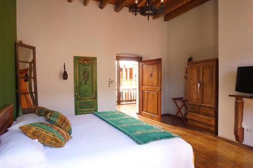 a bedroom with two beds and a television and a door at Casa Alquimia in Quito