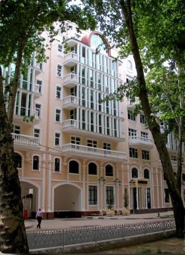 a large pink building with trees in front of it at Poytakht 80 Apartments in Dushanbe